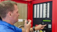 A member of Campus Life Safety and Regulatory Compliance checking the fire panel